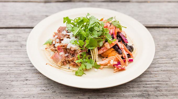 A plate with pork carnitas and roasted yam tacos